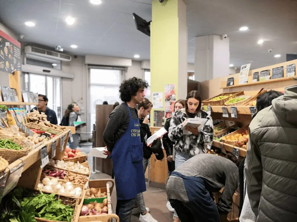 Photo d'un personnel BIOCOOP et de jeunes gens et de rayons de fruits et légumes rayons de fruits et légumes